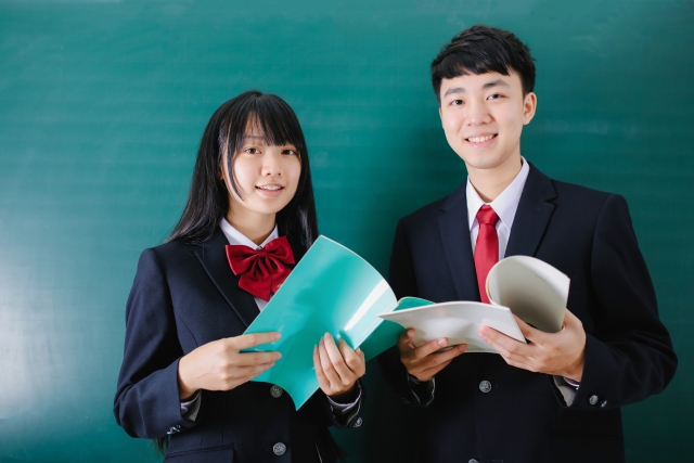 黒板の前で教科書を手にする高校生たち